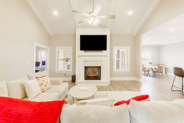 living room with ceiling fan, light hardwood / wood-style flooring, a premium fireplace, and lofted ceiling