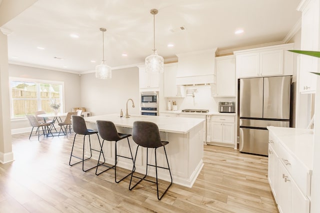 kitchen with white cabinetry, hanging light fixtures, a center island with sink, custom range hood, and appliances with stainless steel finishes