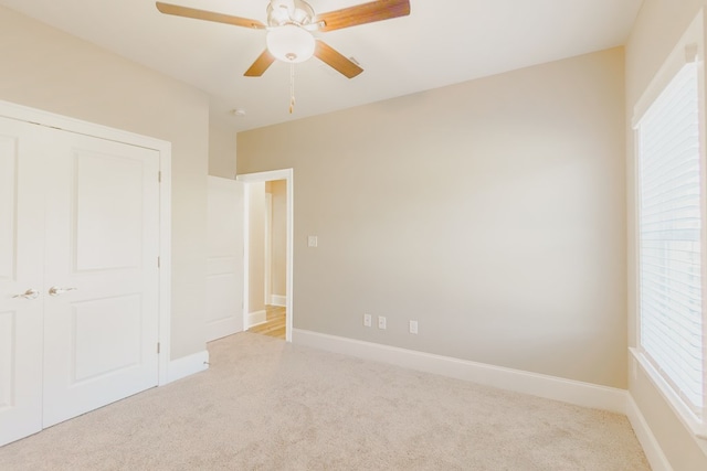 unfurnished bedroom featuring ceiling fan, light carpet, and a closet