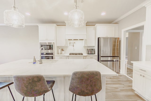 kitchen featuring a center island with sink, crown molding, sink, hanging light fixtures, and stainless steel appliances