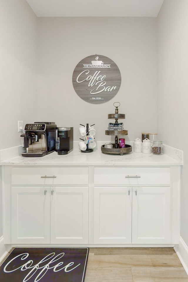 bar featuring light hardwood / wood-style floors and white cabinetry