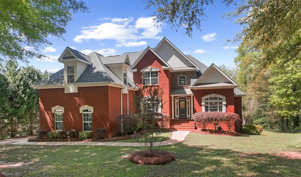 view of front facade with a shingled roof, a front lawn, and brick siding
