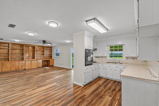 351 Hayborn Rd, Webb, AL 36376 - kitchen with oven, light countertops, ceiling fan, dark wood-style flooring, and white cabinetry