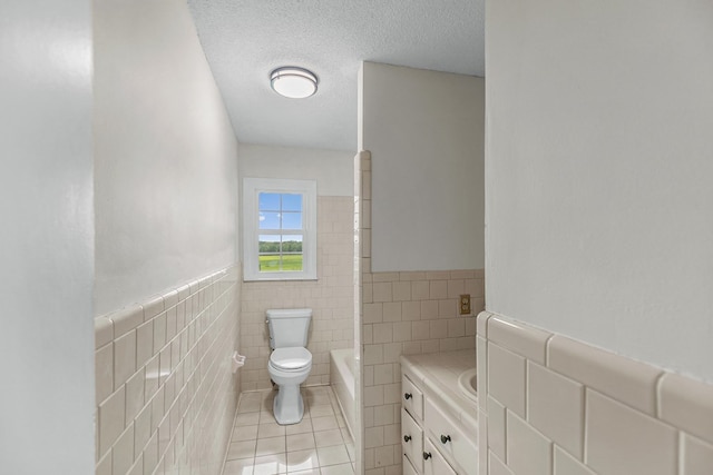 351 Hayborn Rd, Webb, AL 36376 - bathroom with tile walls, tile patterned floors, a bath, a wainscoted wall, and a textured ceiling