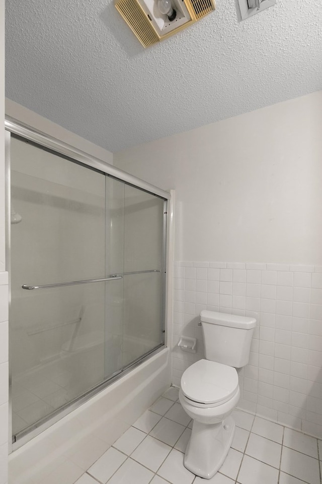 351 Hayborn Rd, Webb, AL 36376 - bathroom featuring tile patterned flooring, bath / shower combo with glass door, a textured ceiling, and a wainscoted wall