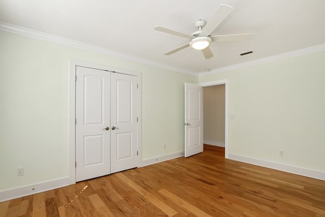 unfurnished bedroom featuring light wood-style floors, baseboards, visible vents, and crown molding