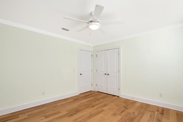 spare room featuring light wood finished floors, visible vents, and ornamental molding