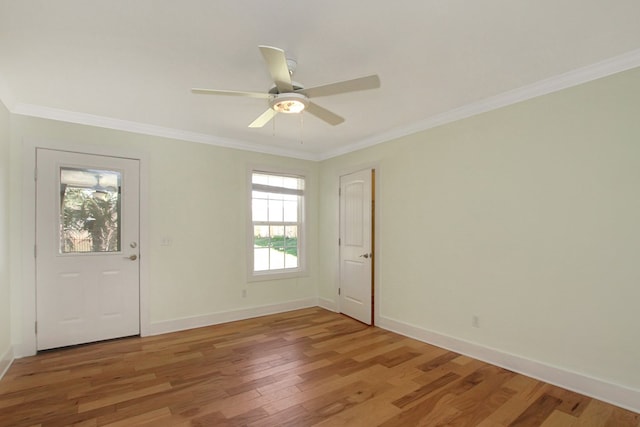 spare room featuring ornamental molding, light wood-style flooring, baseboards, and a ceiling fan