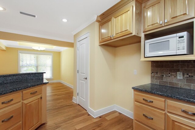 kitchen featuring white microwave, light wood-style flooring, visible vents, ornamental molding, and decorative backsplash