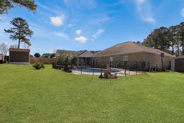 view of yard featuring an outbuilding, a storage unit, a fenced backyard, and a fenced in pool