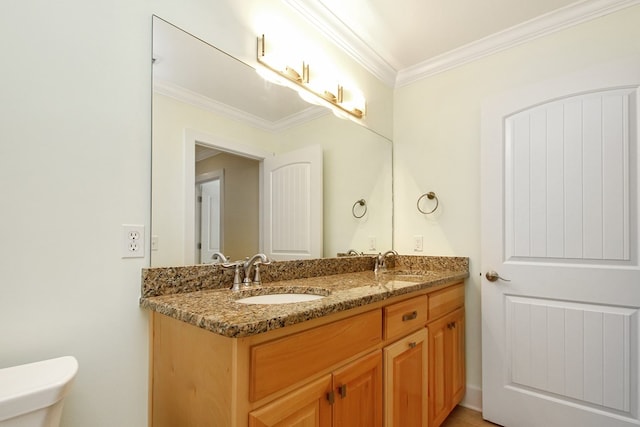 bathroom with double vanity, a sink, toilet, and crown molding