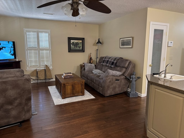 living room featuring ceiling fan, dark hardwood / wood-style flooring, sink, and a textured ceiling