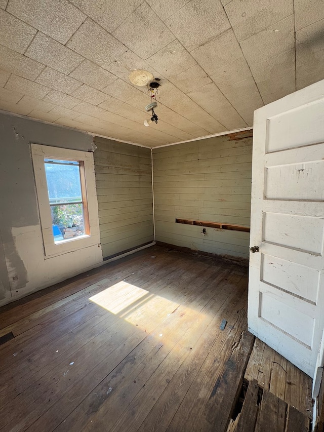 unfurnished room featuring wood walls and dark wood-type flooring