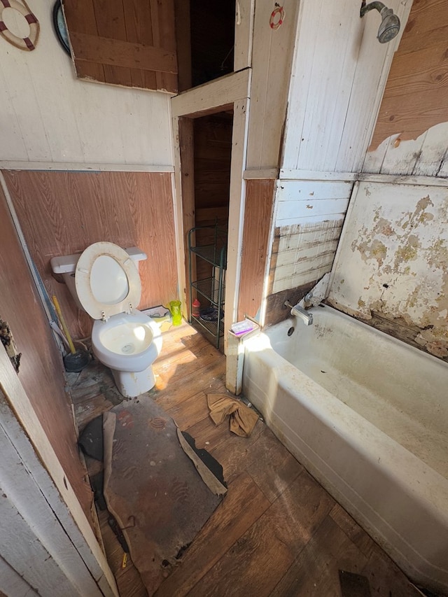 bathroom with toilet, wood walls, and shower / washtub combination