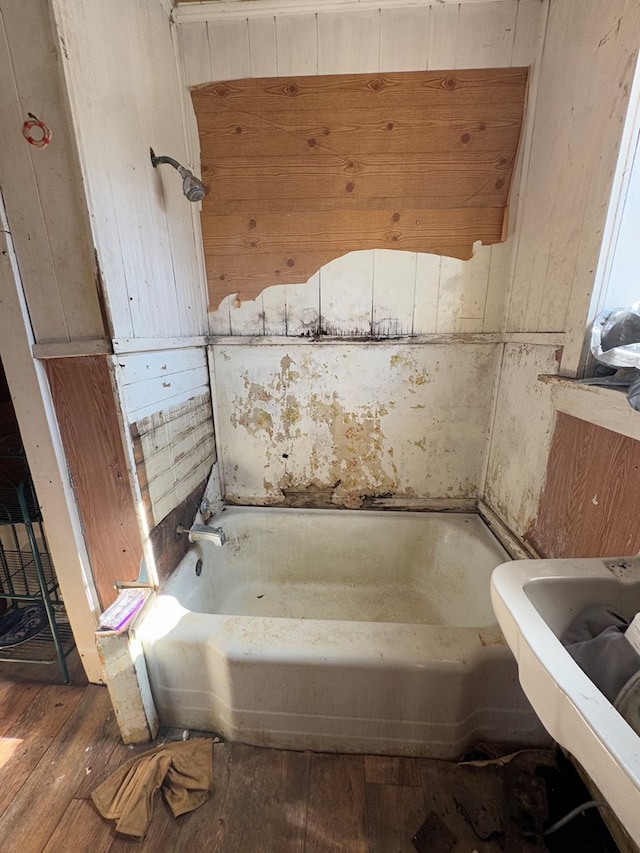 bathroom featuring wood-type flooring and a tub to relax in