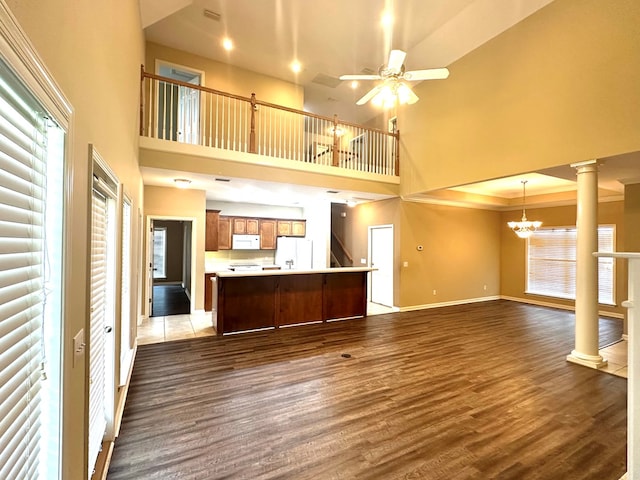 208 Planters Ct, Enterprise, AL 36330 - unfurnished living room featuring dark wood-style flooring, decorative columns, a towering ceiling, a chandelier, and a ceiling fan