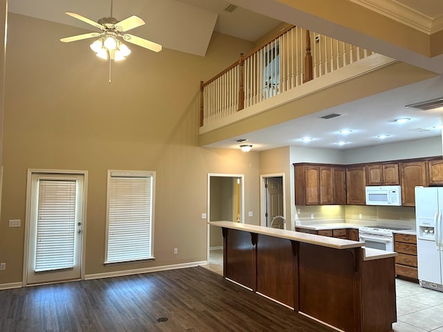 208 Planters Ct, Enterprise, AL 36330 - kitchen with white appliances, a towering ceiling, a ceiling fan, light countertops, and a breakfast bar area