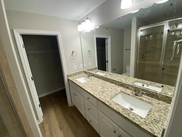 bathroom with a shower with door, vanity, wood-type flooring, and toilet