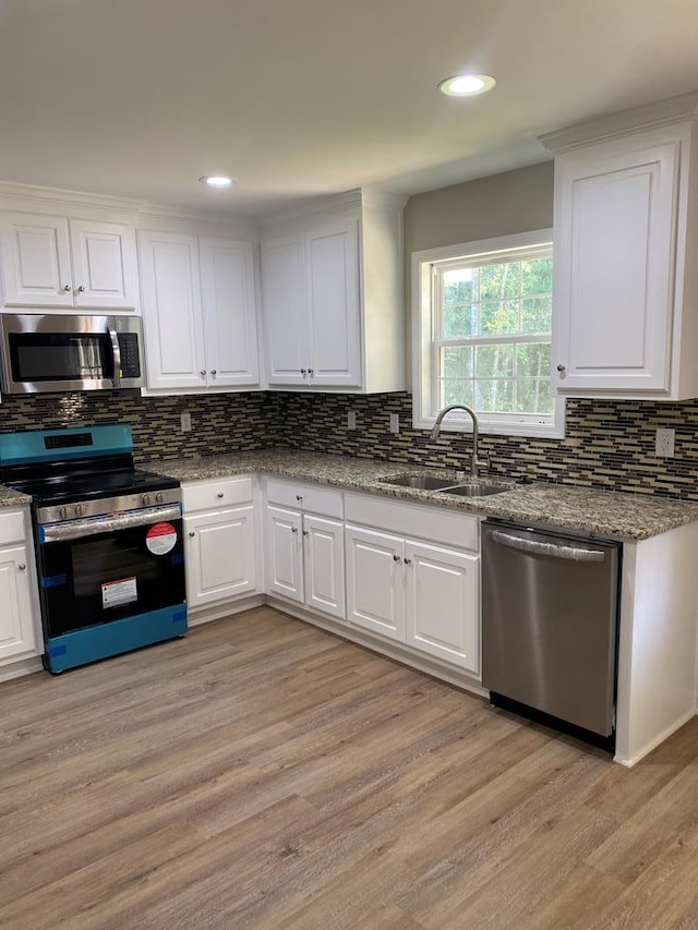 kitchen featuring sink, white cabinets, stainless steel appliances, and light wood-type flooring