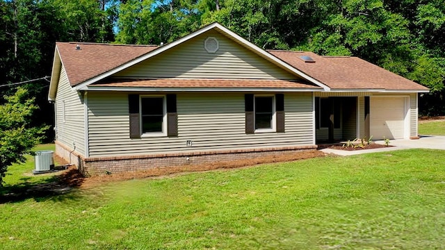 back of property with central AC unit, a garage, and a yard