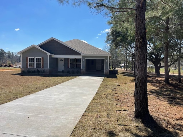 view of front of property featuring an attached garage, brick siding, a shingled roof, driveway, and a front yard