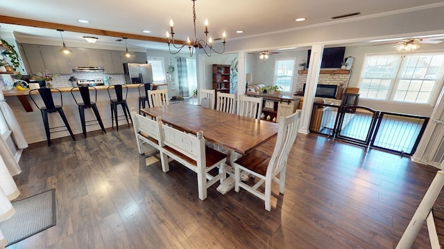 dining area with ceiling fan, visible vents, dark wood-style flooring, and a stone fireplace