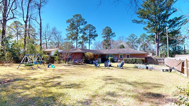 rear view of house featuring playground community, a lawn, and fence