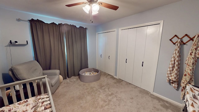 carpeted bedroom featuring ceiling fan and two closets