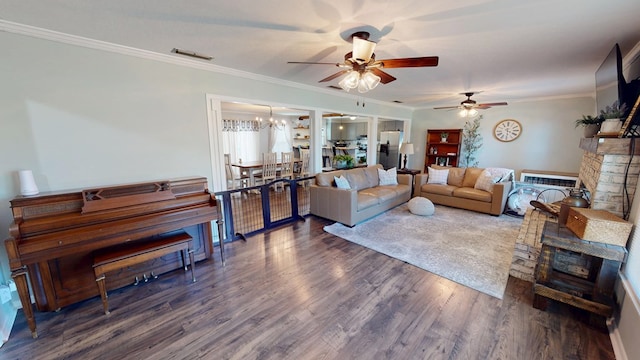 living room with ceiling fan with notable chandelier, wood finished floors, visible vents, ornamental molding, and a brick fireplace