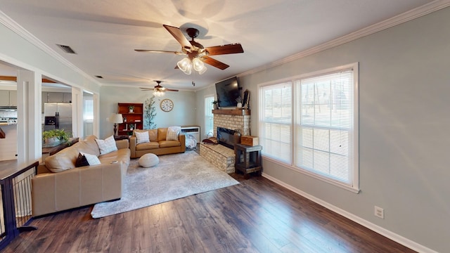 living area with crown molding, visible vents, wood finished floors, and a stone fireplace