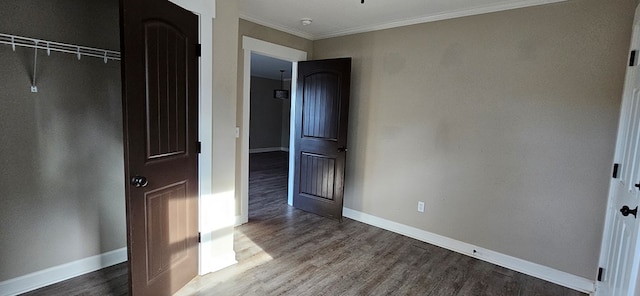 unfurnished bedroom with crown molding, a closet, and hardwood / wood-style flooring