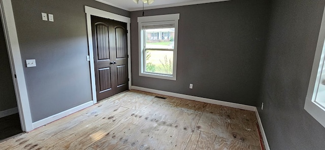 empty room with ornamental molding and light wood-type flooring