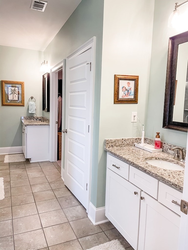 bathroom featuring baseboards, visible vents, a sink, tile patterned flooring, and two vanities