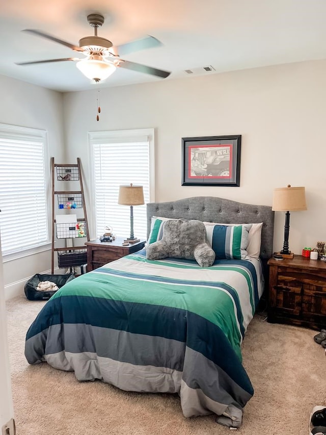 bedroom with ceiling fan, carpet floors, multiple windows, and visible vents