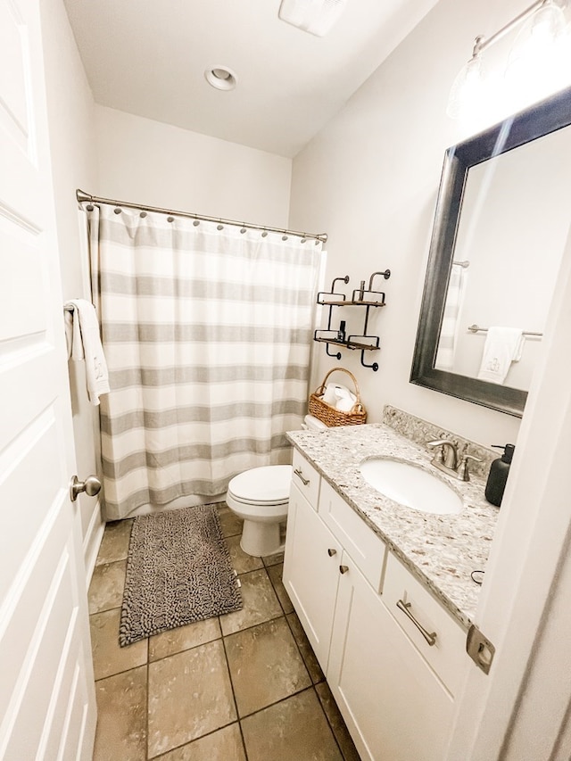 bathroom with toilet, vanity, and tile patterned floors