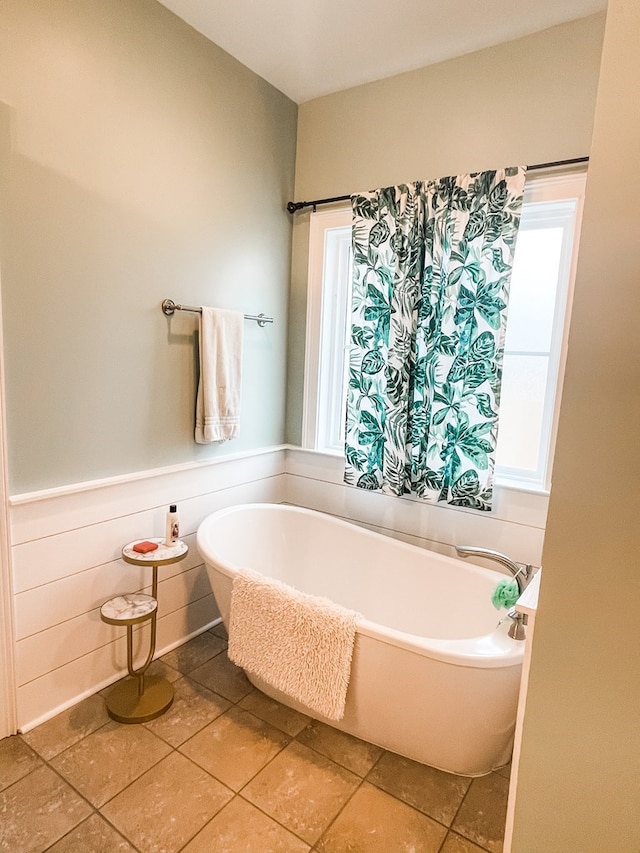 bathroom featuring wainscoting and a soaking tub