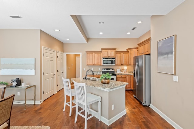 328 Hidden Creek Cir, Dothan, AL 36301 - kitchen featuring appliances with stainless steel finishes, dark wood finished floors, a kitchen island with sink, recessed lighting, and light stone countertops