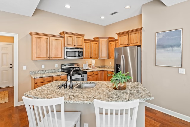 328 Hidden Creek Cir, Dothan, AL 36301 - kitchen with stainless steel appliances, dark wood-style floors, recessed lighting, a breakfast bar area, and light stone countertops