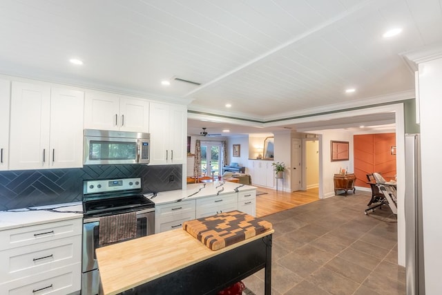 kitchen featuring white cabinets, stainless steel appliances, tasteful backsplash, and ornamental molding