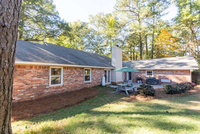 back of property with a yard and a patio