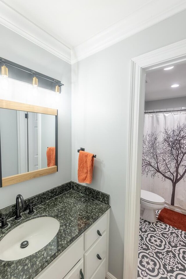 bathroom featuring vanity, toilet, and ornamental molding