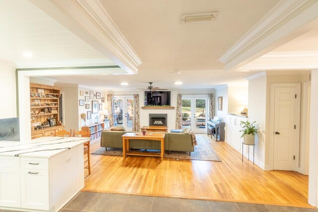 living room featuring french doors, crown molding, ceiling fan, built in features, and light hardwood / wood-style floors