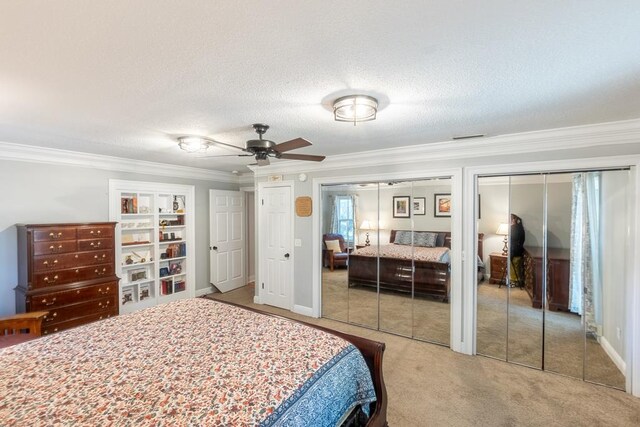 bedroom with crown molding, ceiling fan, a textured ceiling, carpet floors, and multiple closets