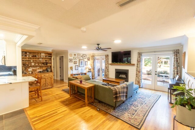 living room with crown molding, ceiling fan, french doors, and wood-type flooring