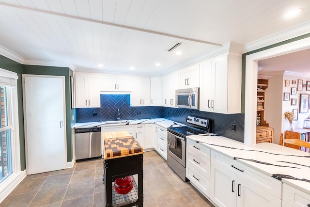 kitchen with white cabinets, sink, decorative backsplash, dark tile patterned floors, and appliances with stainless steel finishes