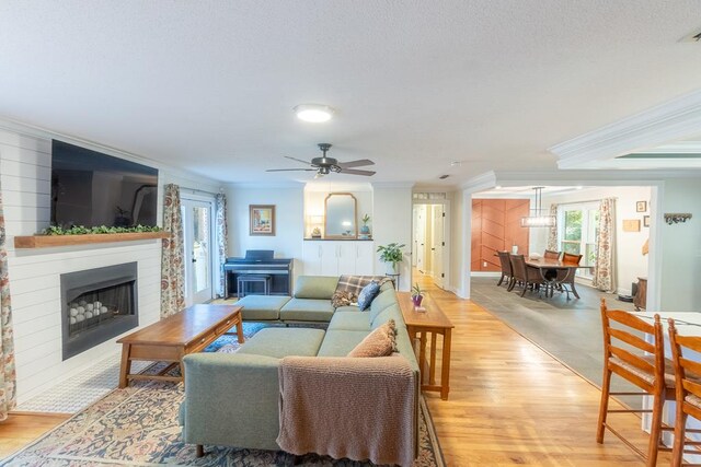 living room featuring a wealth of natural light, crown molding, and ceiling fan