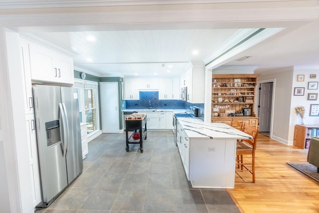 kitchen featuring a kitchen breakfast bar, stainless steel appliances, white cabinetry, and a kitchen island