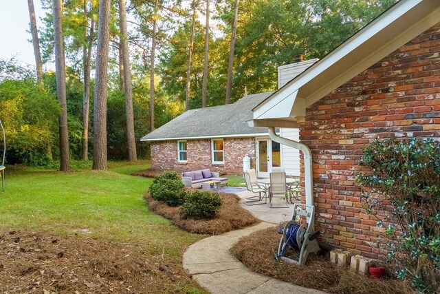 view of yard featuring an outdoor living space, a trampoline, and a patio area