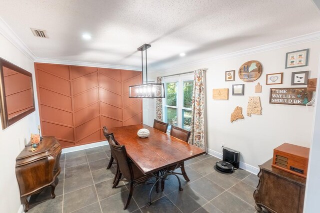 dining area featuring a textured ceiling, dark tile patterned floors, and crown molding