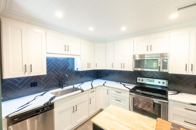 kitchen featuring decorative backsplash, appliances with stainless steel finishes, ornamental molding, sink, and white cabinets